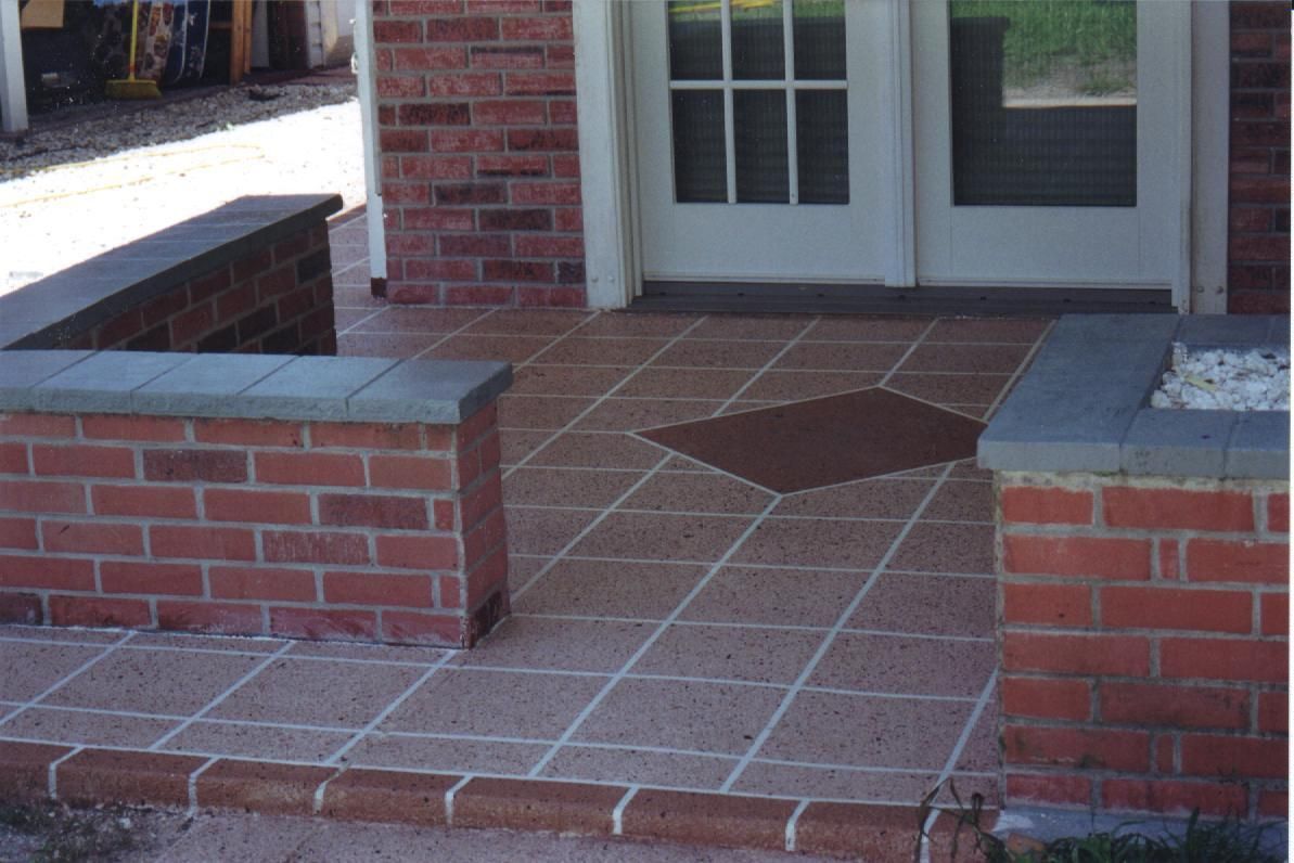 Brick-front porch with tiled floor, low brick walls, and white double doors