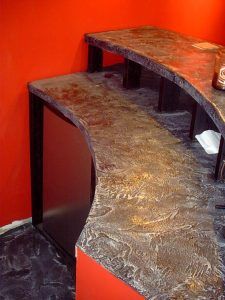 Curved wooden desk with dark shelves against a bright red wall.