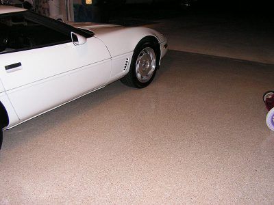 White sports car parked at night on a driveway, with a small red-and-white object at the right edge.
