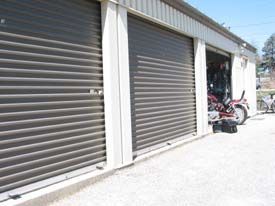 A row of garage doors with a motorcycle parked in one of them.