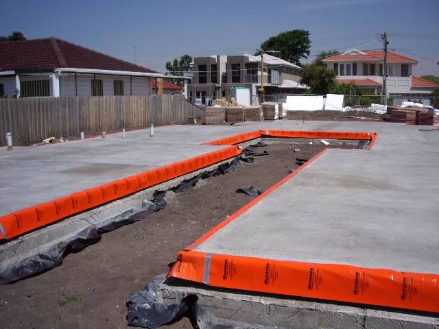 A concrete floor with orange barriers around it and houses in the background — Advanced Pest Control Wollongong in Albion Park Rail, NSW