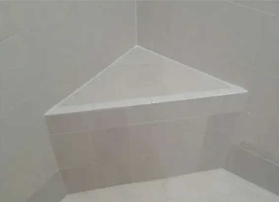 There is a triangle shaped shelf in the corner of a bathroom.