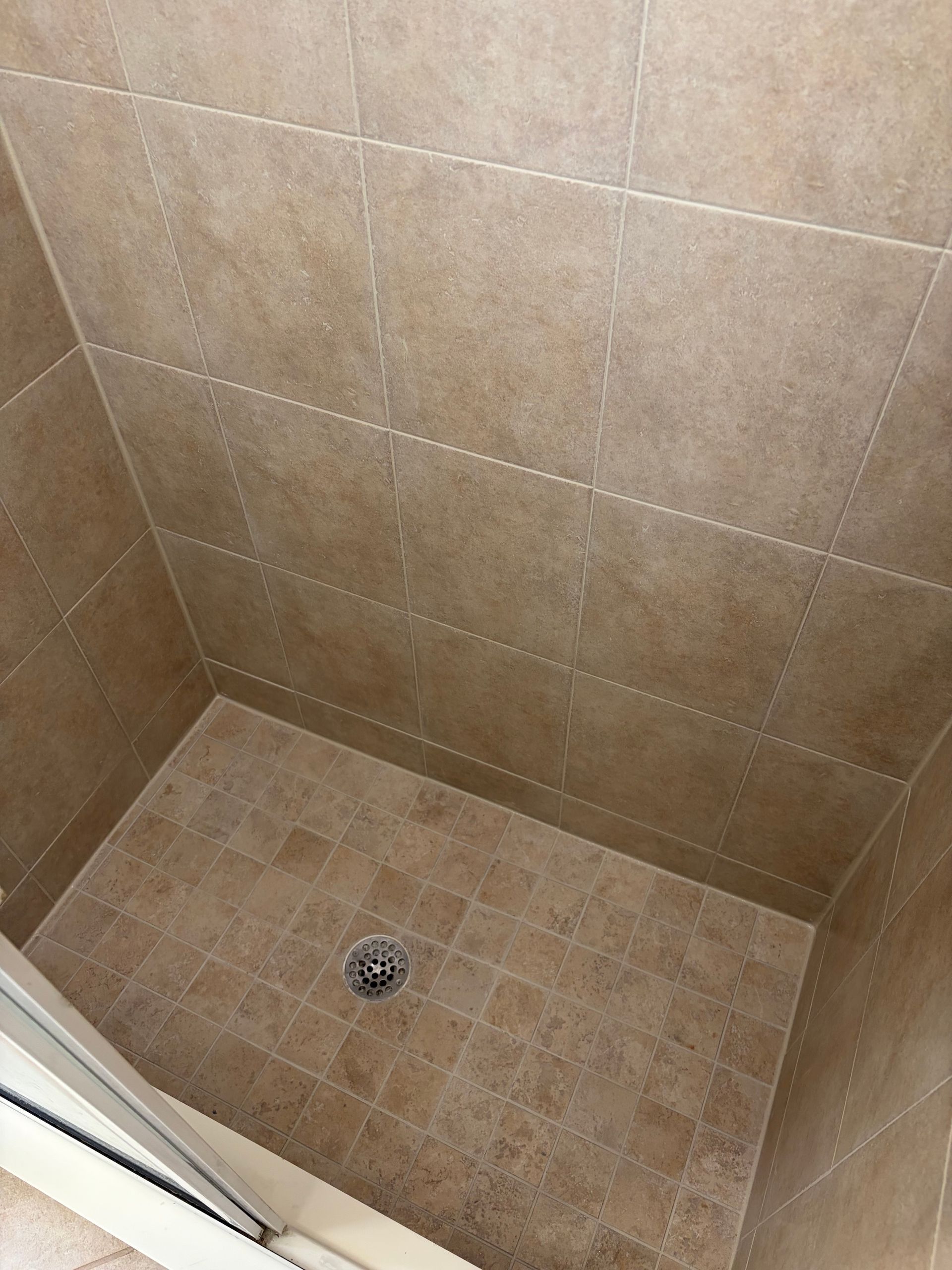White tiled shower wall with gray grout.
