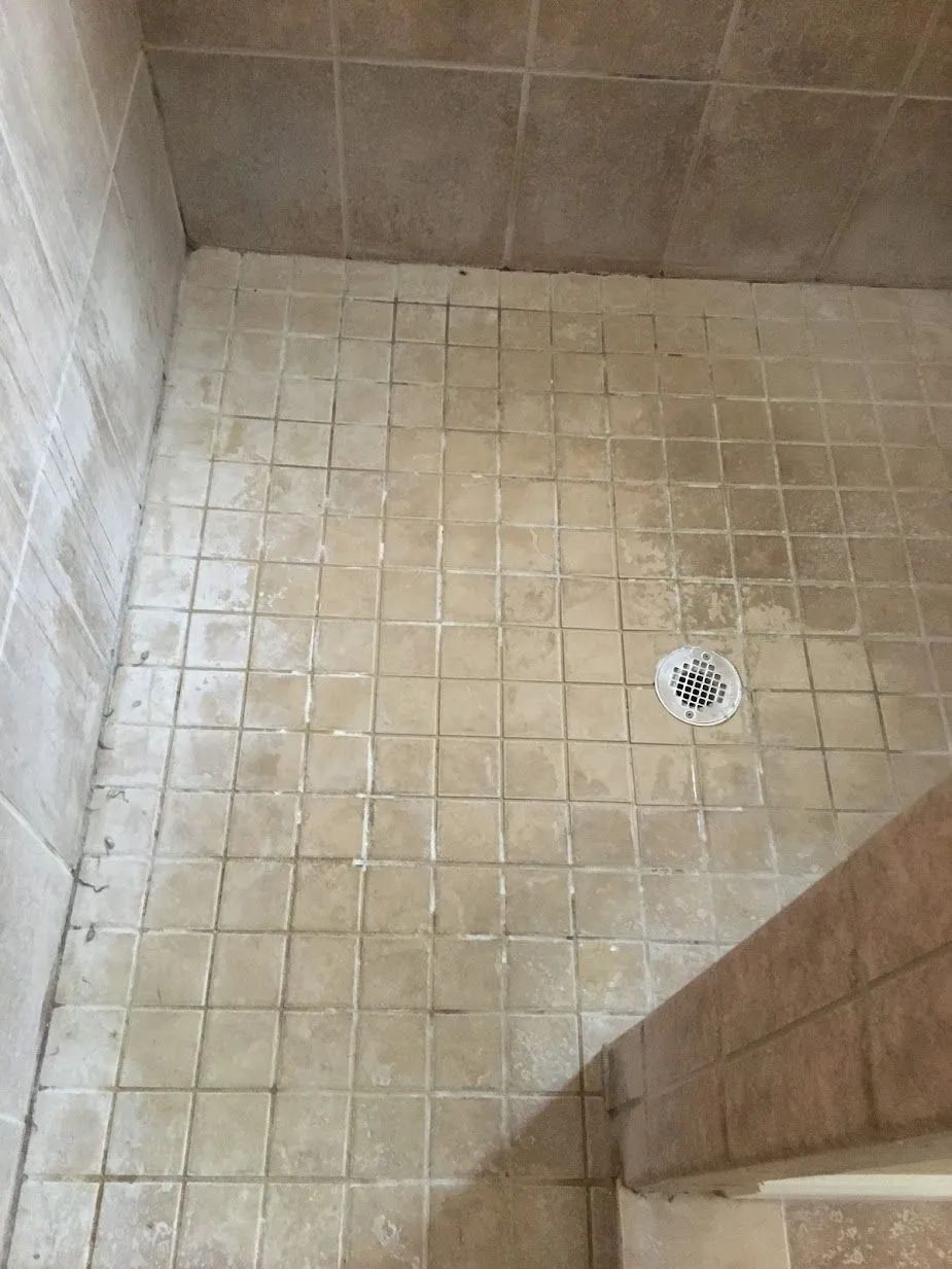 Small tiled shower floor with a drain in the corner.