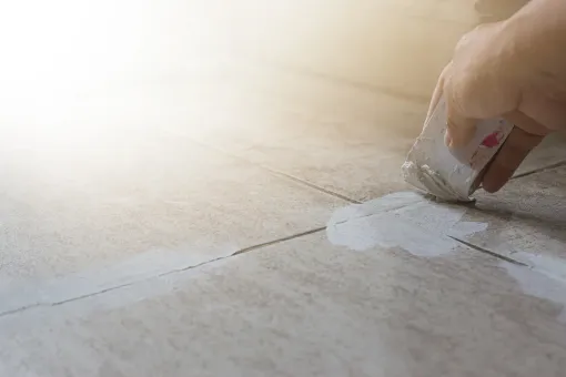 A person is cleaning a tile floor with a sponge.