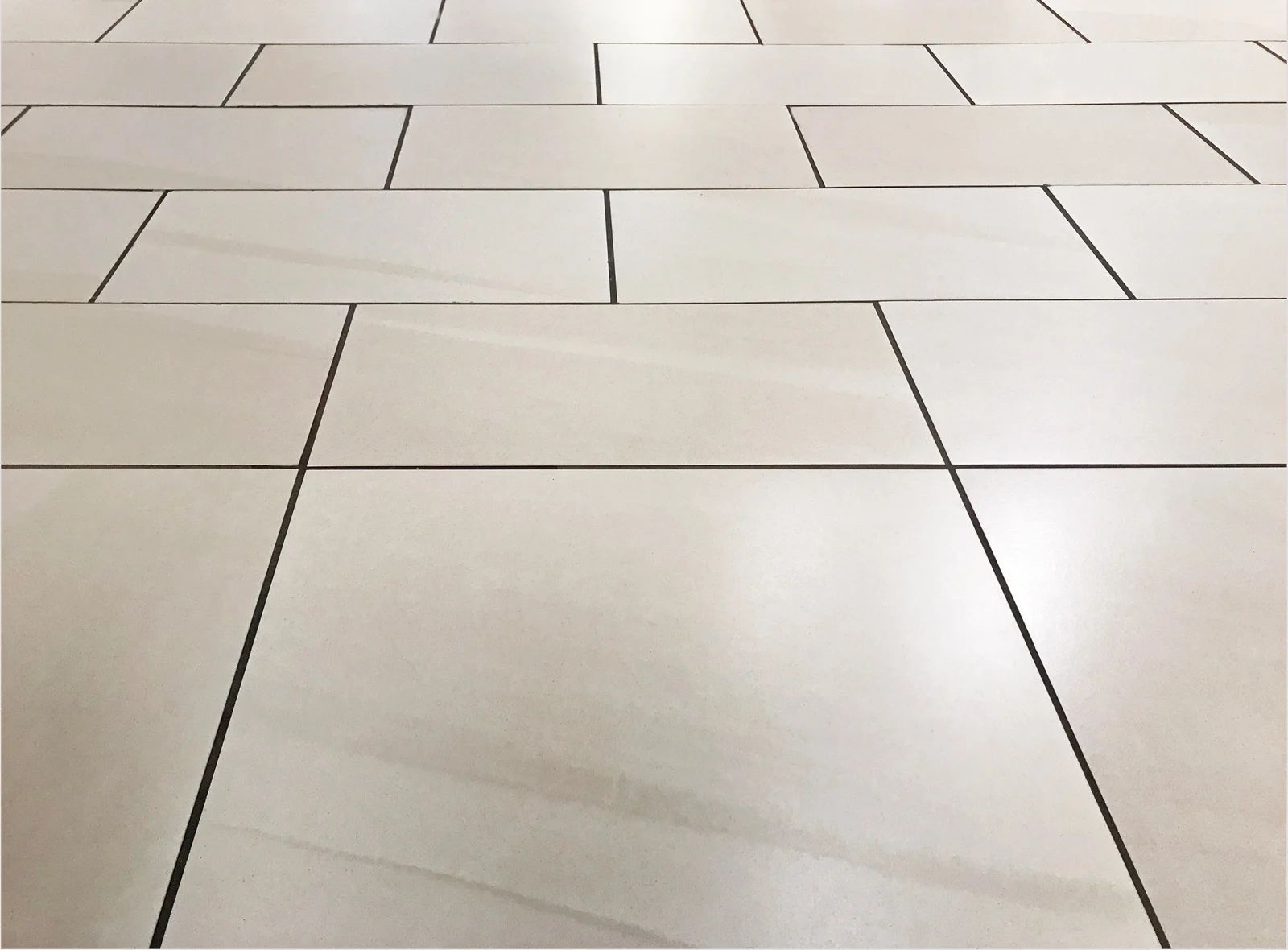 Light beige tiled floor with dark grout lines forming a geometric pattern.