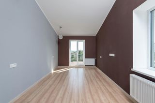 Empty modern room with light wood floor, gray and brown walls, and glass doors at the far end.