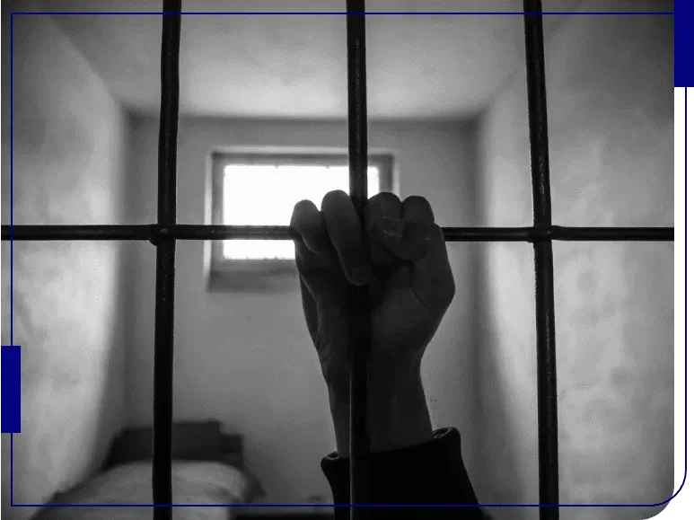 A hand is behind bars in a prison cell