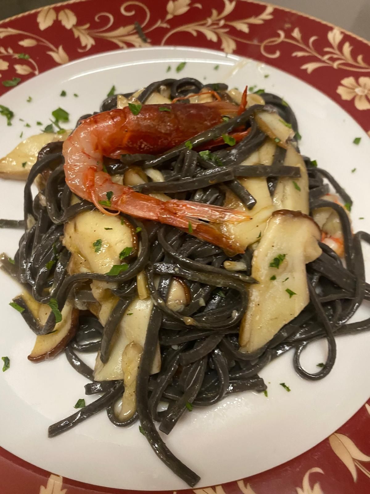 Scampi disposti su un piatto bianco, conditi con olio ed erbe aromatiche. Contesto della cena, primo piano.