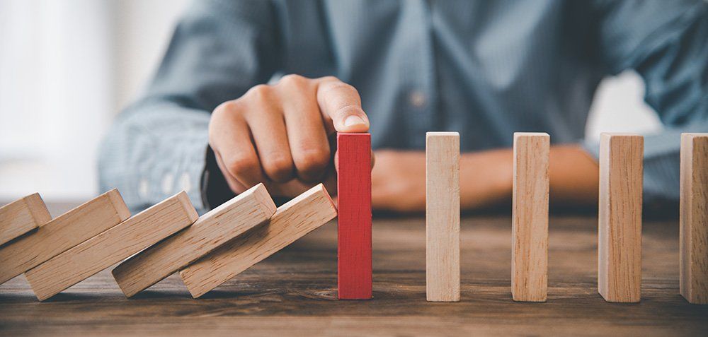 A person is playing with wooden blocks on a wooden table.