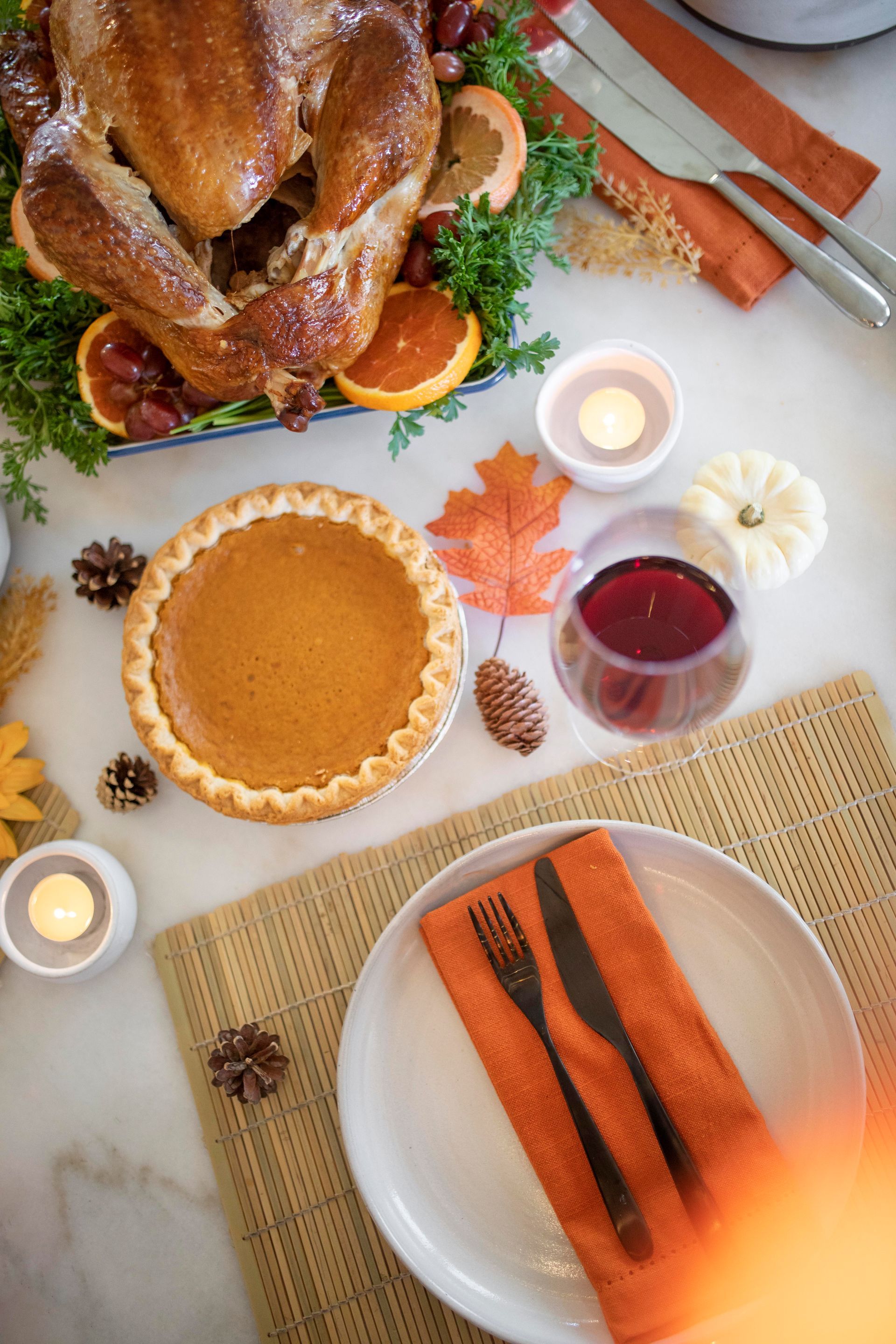 Thanksgiving table: Roasted turkey, pumpkin pie, place setting, wine, and fall decorations.