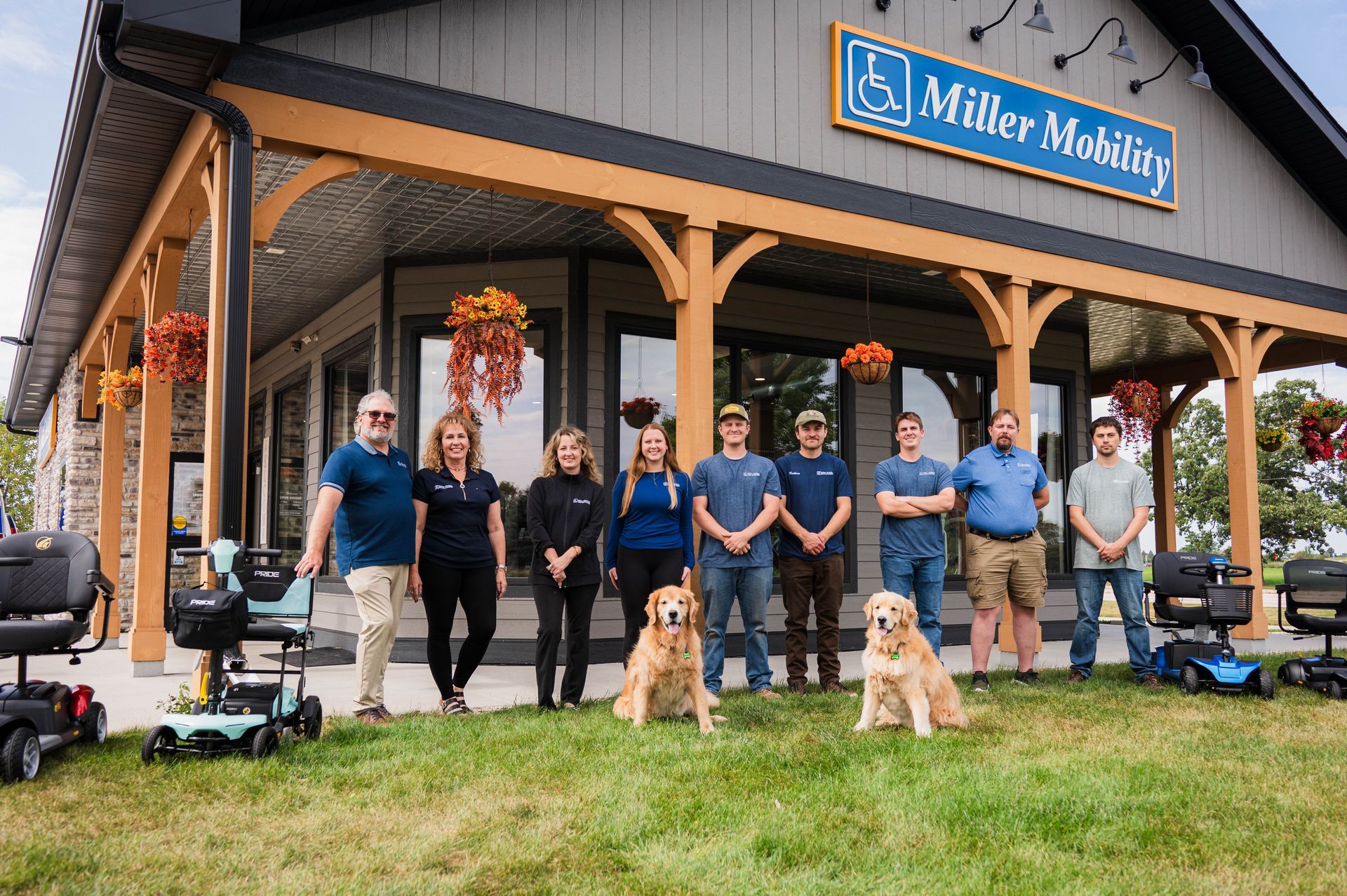 Miller Mobility staff with mobility devices, golden retrievers, and building with sign.