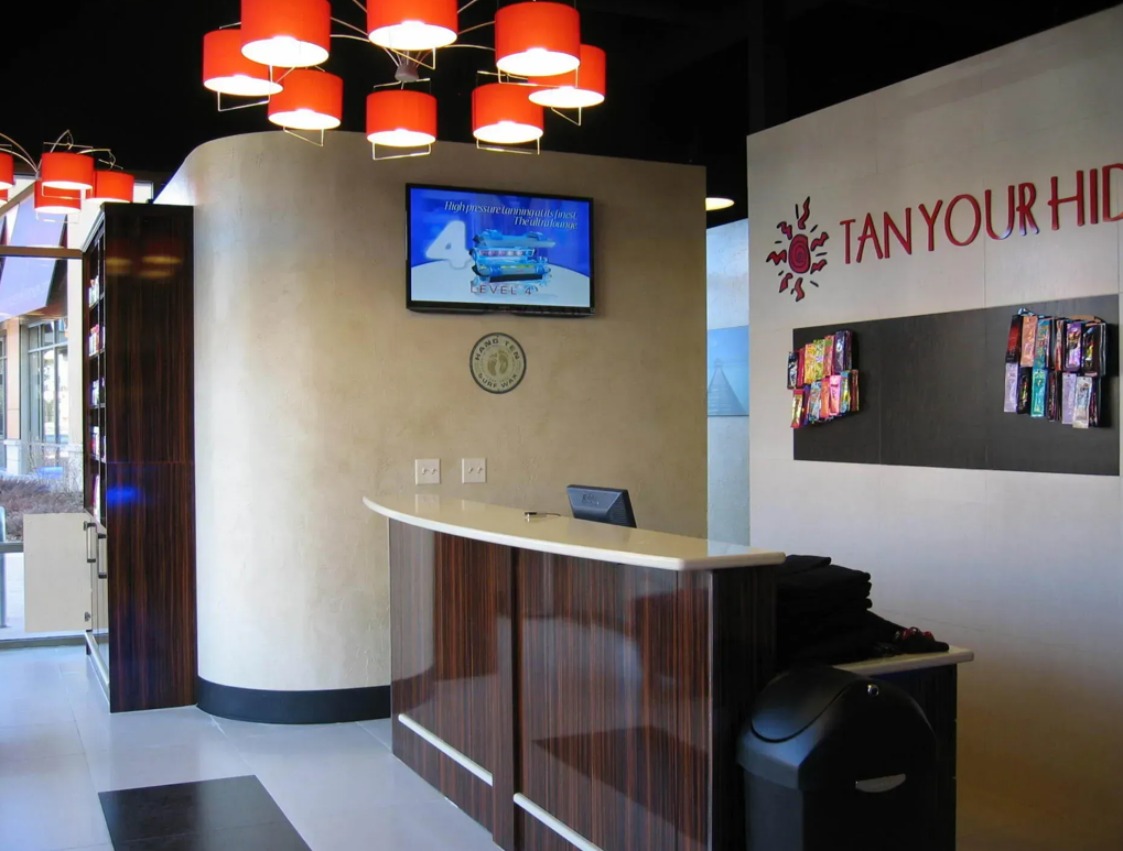A salon reception area featuring a wooden front desk and a sign reading A salon reception area featuring a wooden front desk and a sign reading