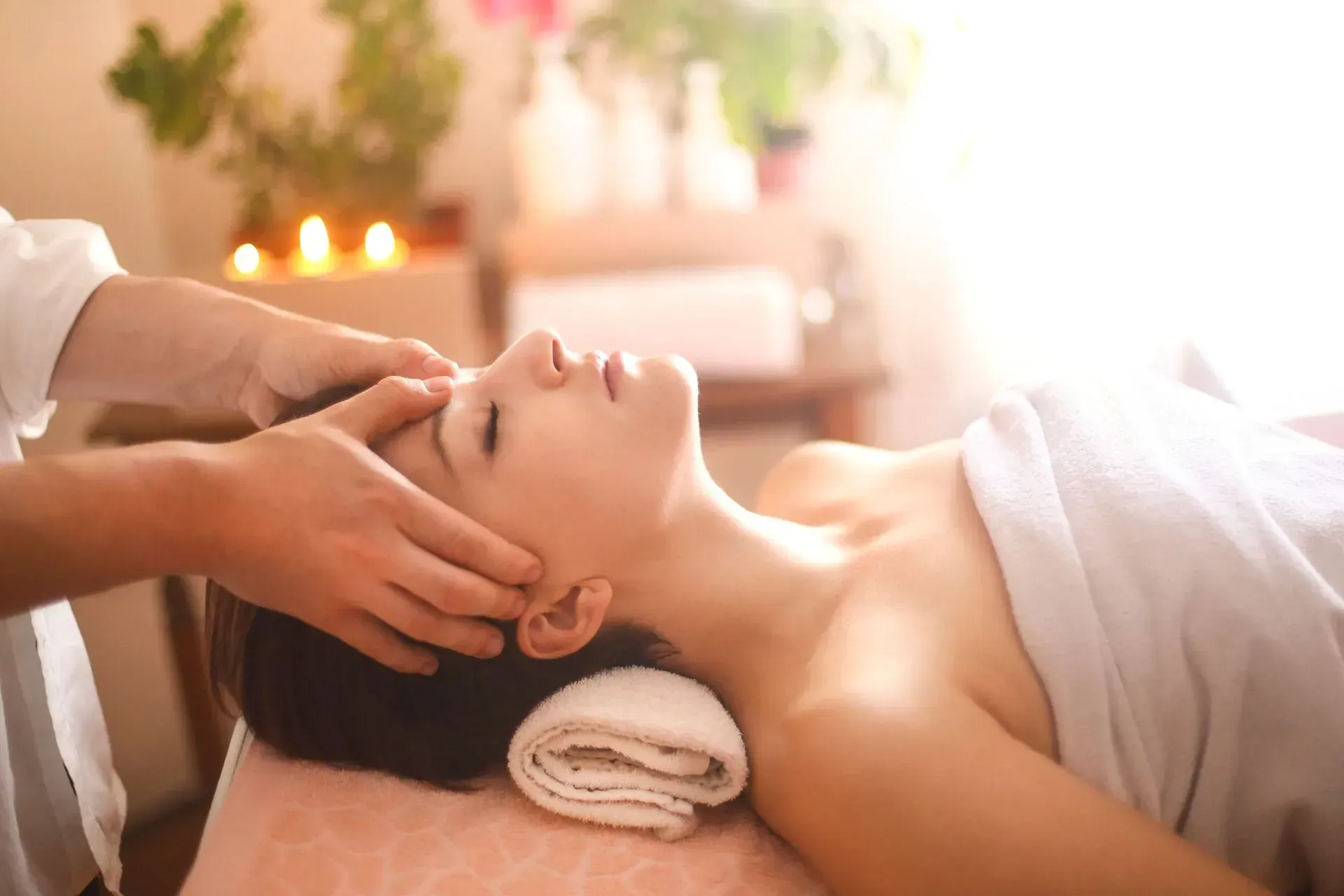 Woman receiving a head massage on a spa bed, lit by sunlight. Woman receiving a head massage on a spa bed, lit by sunlight.
