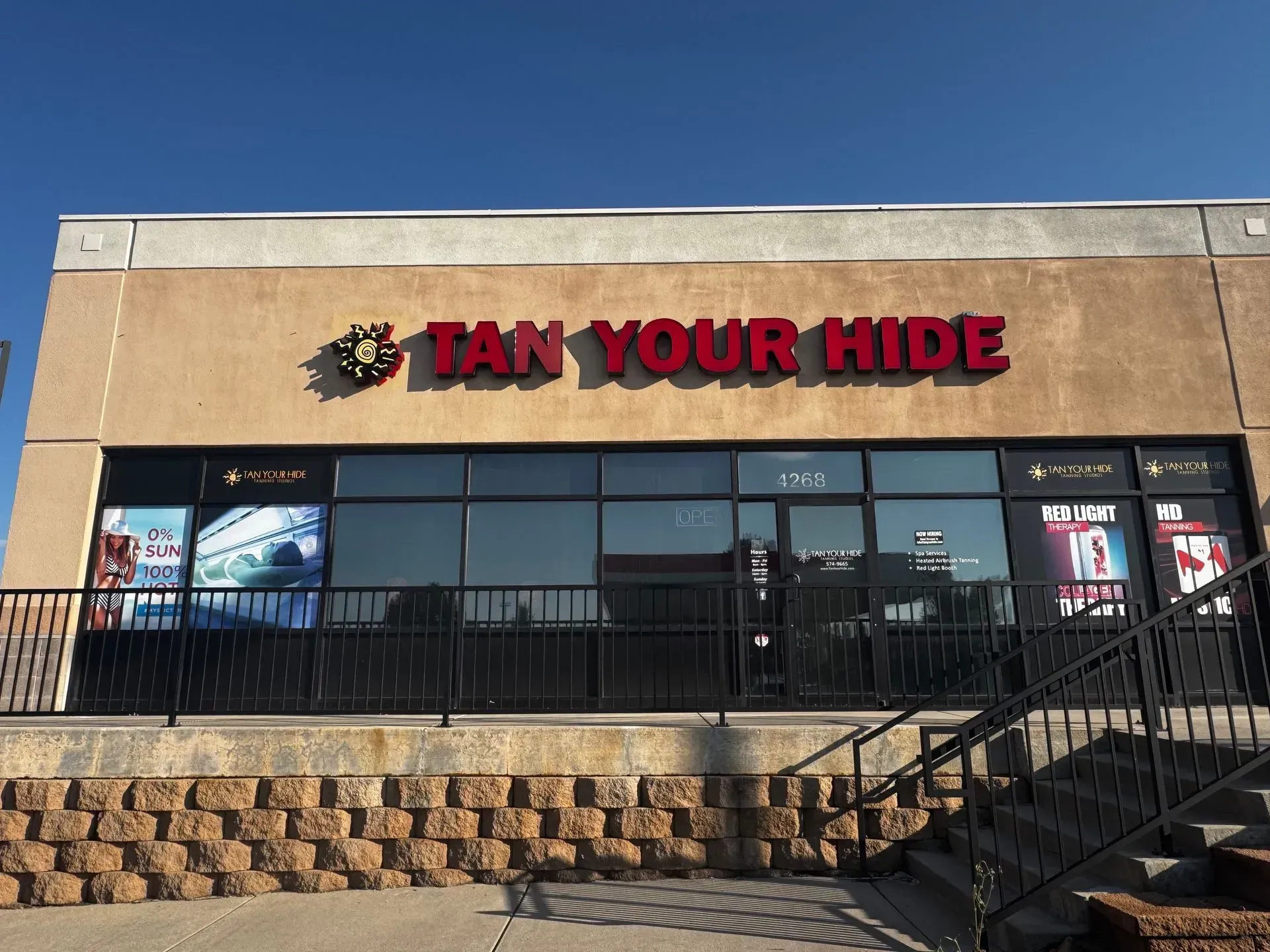 Tan Your Hide storefront with red lettering and logo above a glass window.