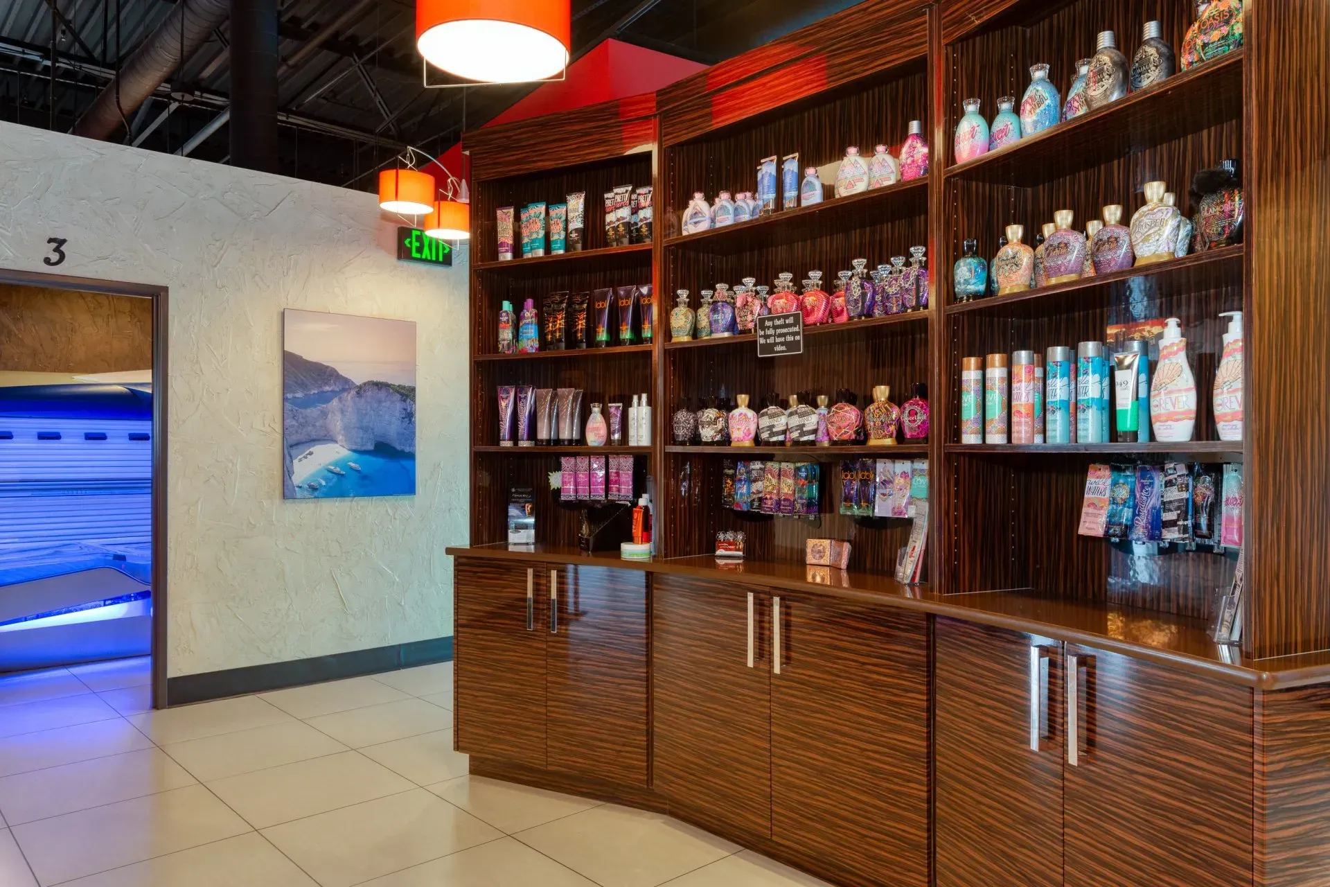 Tanning salon interior with shelves of lotions and a tanning bed visible.