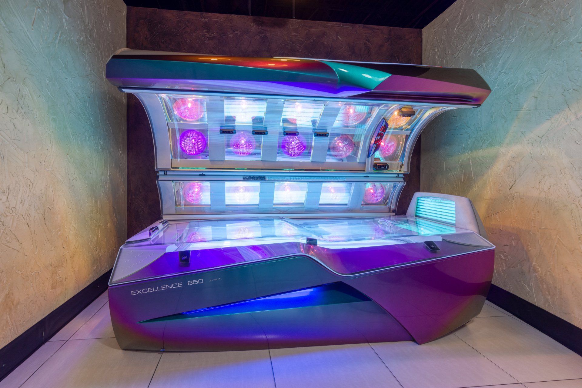 Purple and blue tanning bed in a room with beige walls.