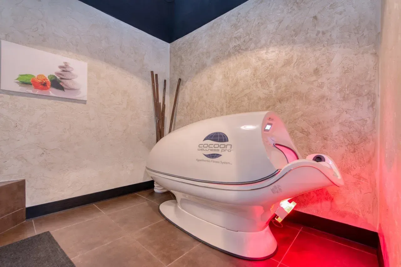 White spa bed in a room with neutral walls, lit with red light.