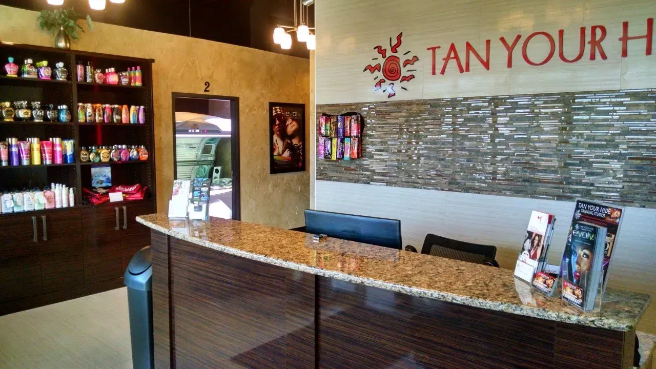 Interior of a tanning salon with a front desk, display of tanning products, and the words 