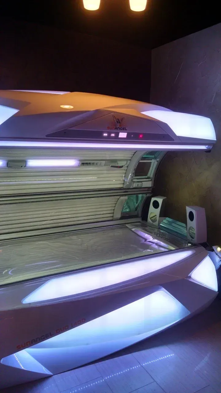 Tanning bed, silver and blue lights, inside a dark room.