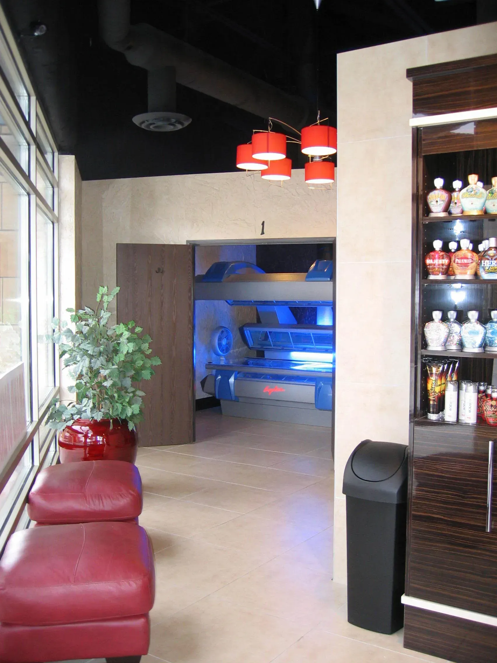 Interior of a tanning salon with tanning beds, red accents, and product display.