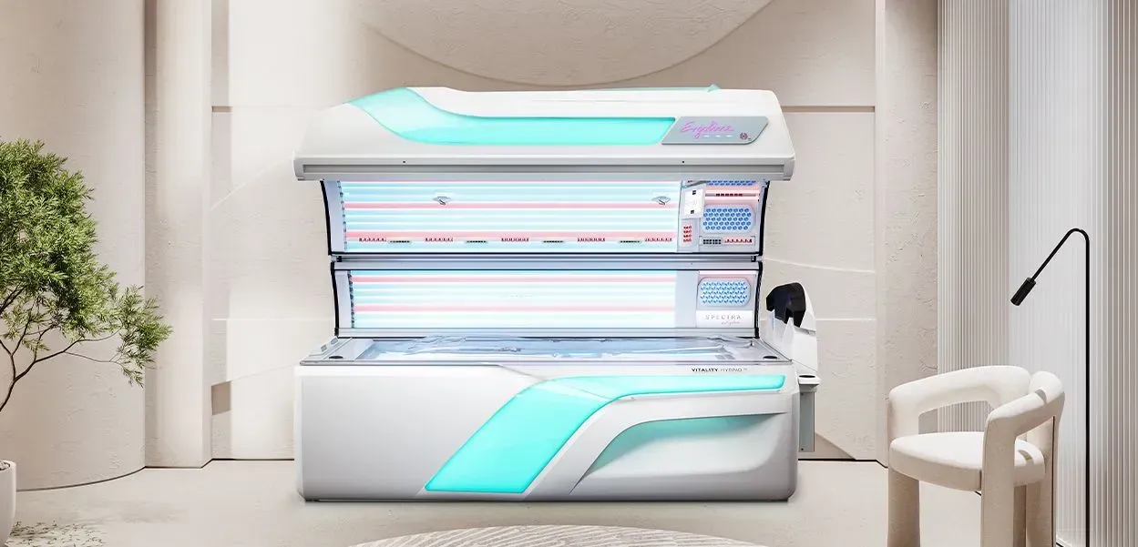 A tanning bed with blue accents sits in a minimalist room with a chair and a plant.