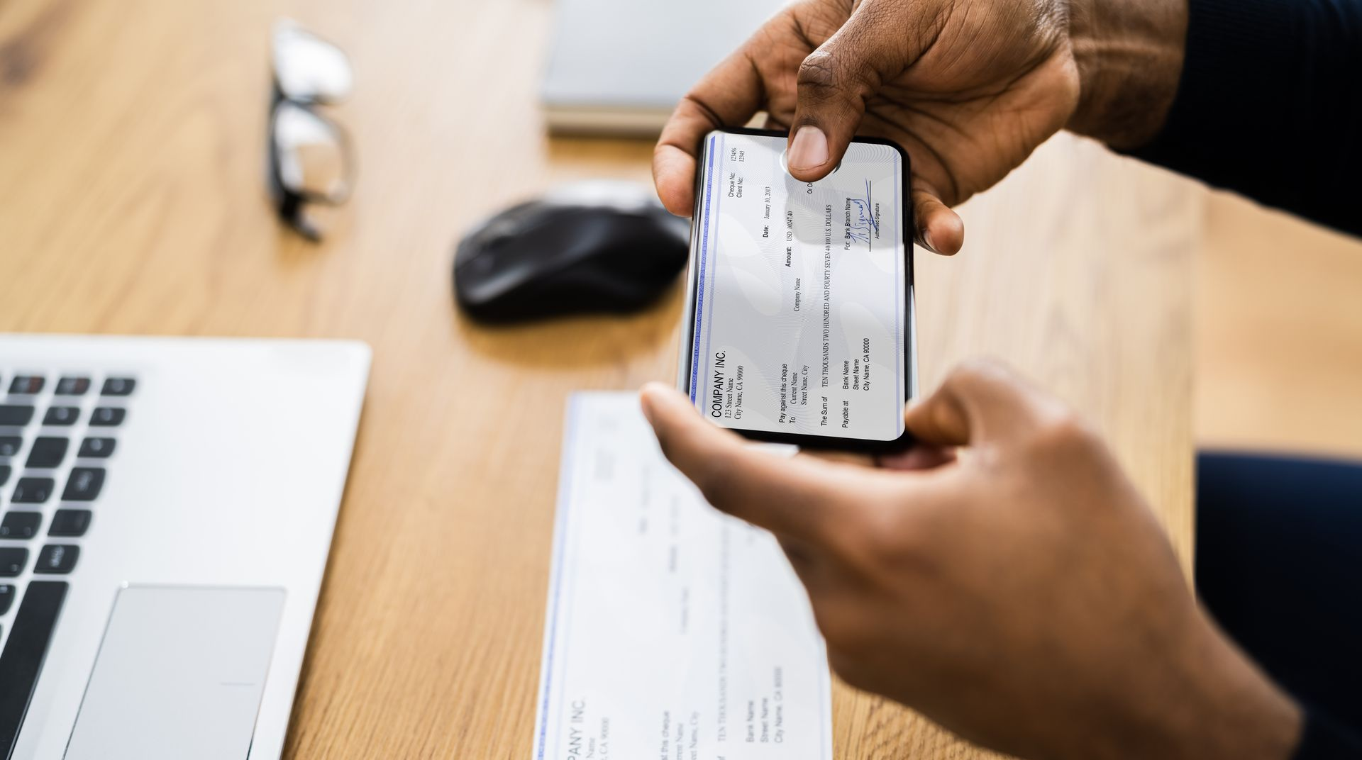 Hands holding a credit card over a laptop and check on a desk