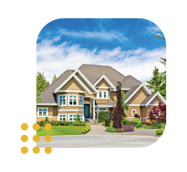 Large suburban house with stone and wood exterior, manicured lawn, and blue sky with clouds