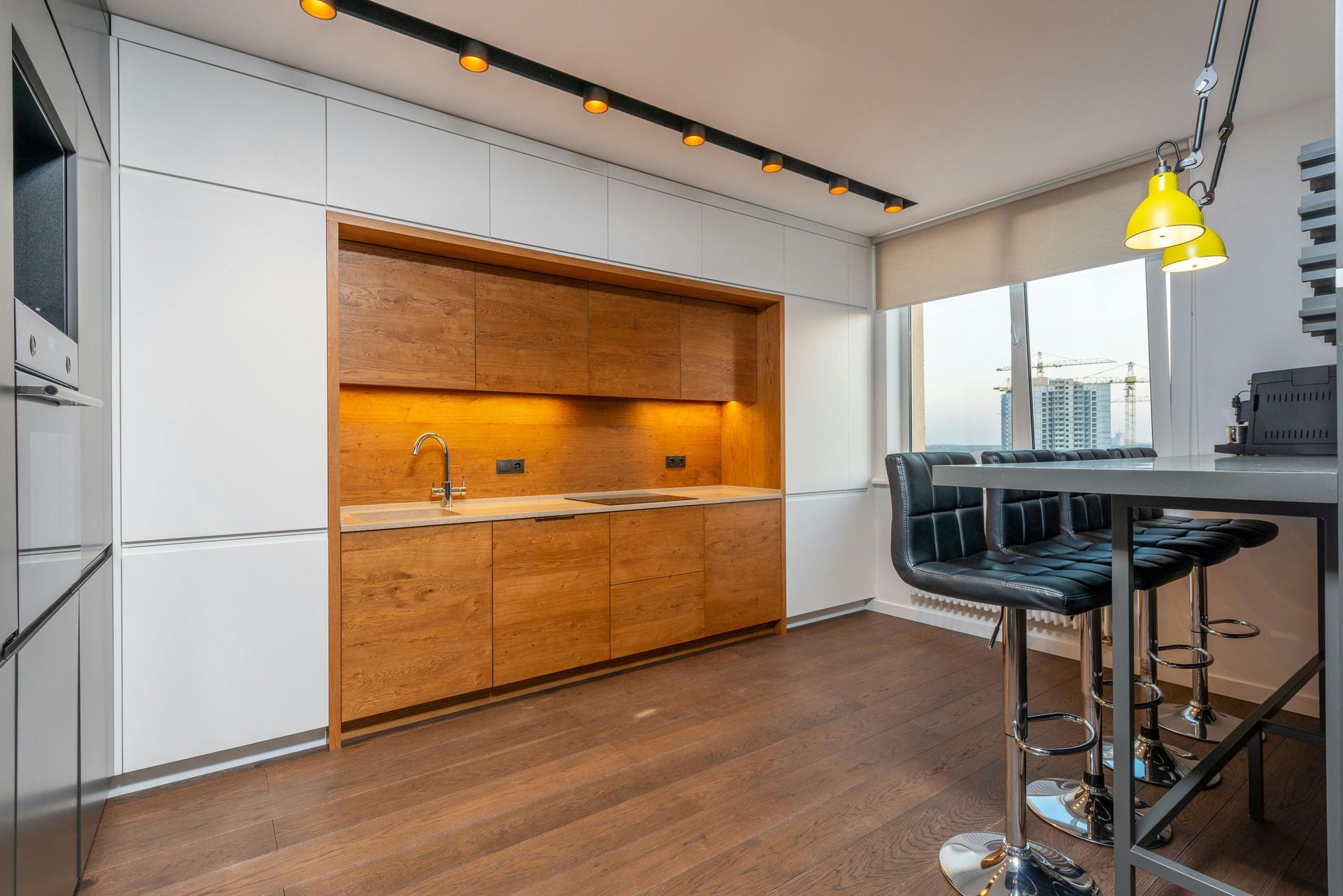 Modern kitchen with wood cabinets, a breakfast bar, and a city view.