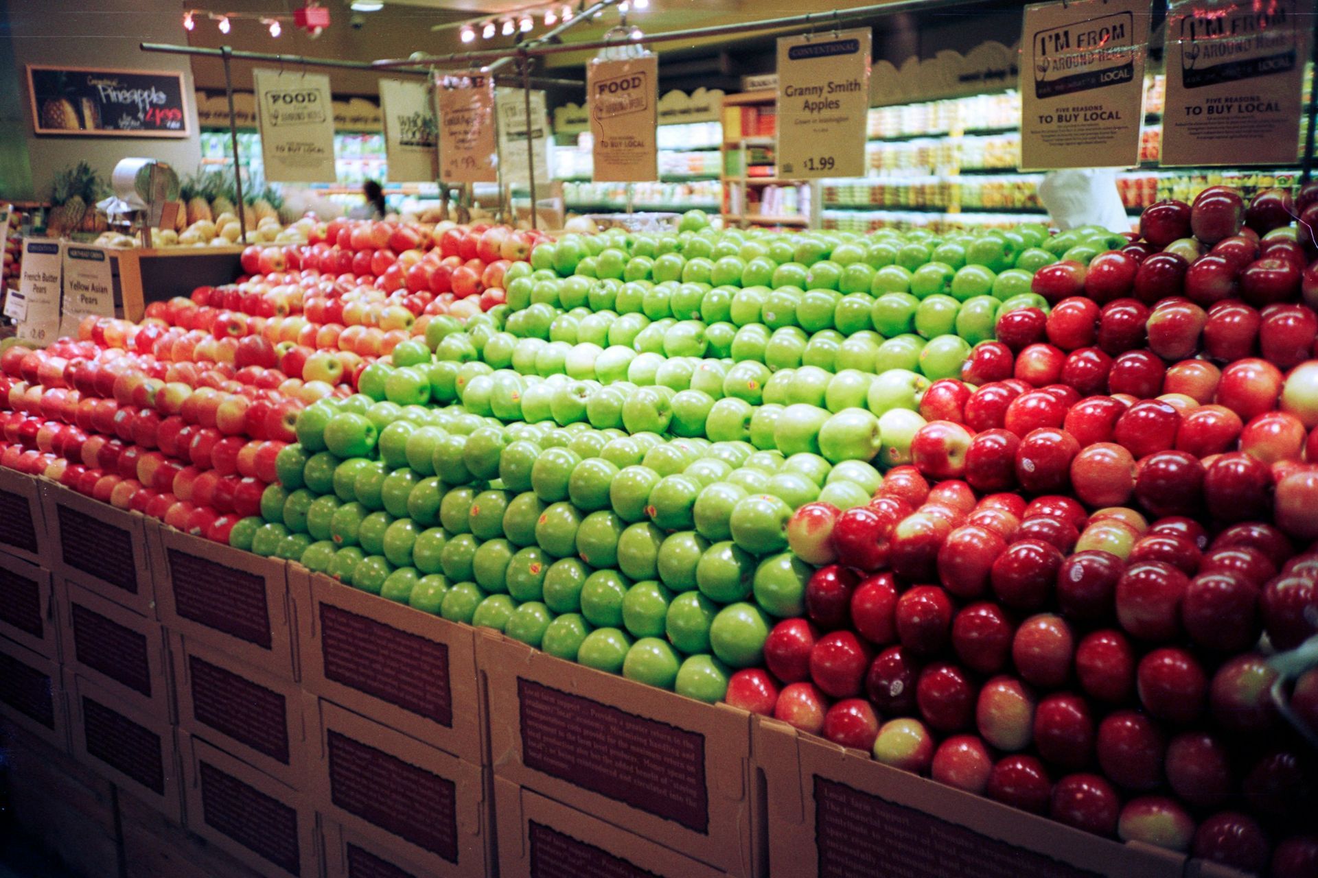 Close up of a supermarket aisle showing three types of apples stacked high