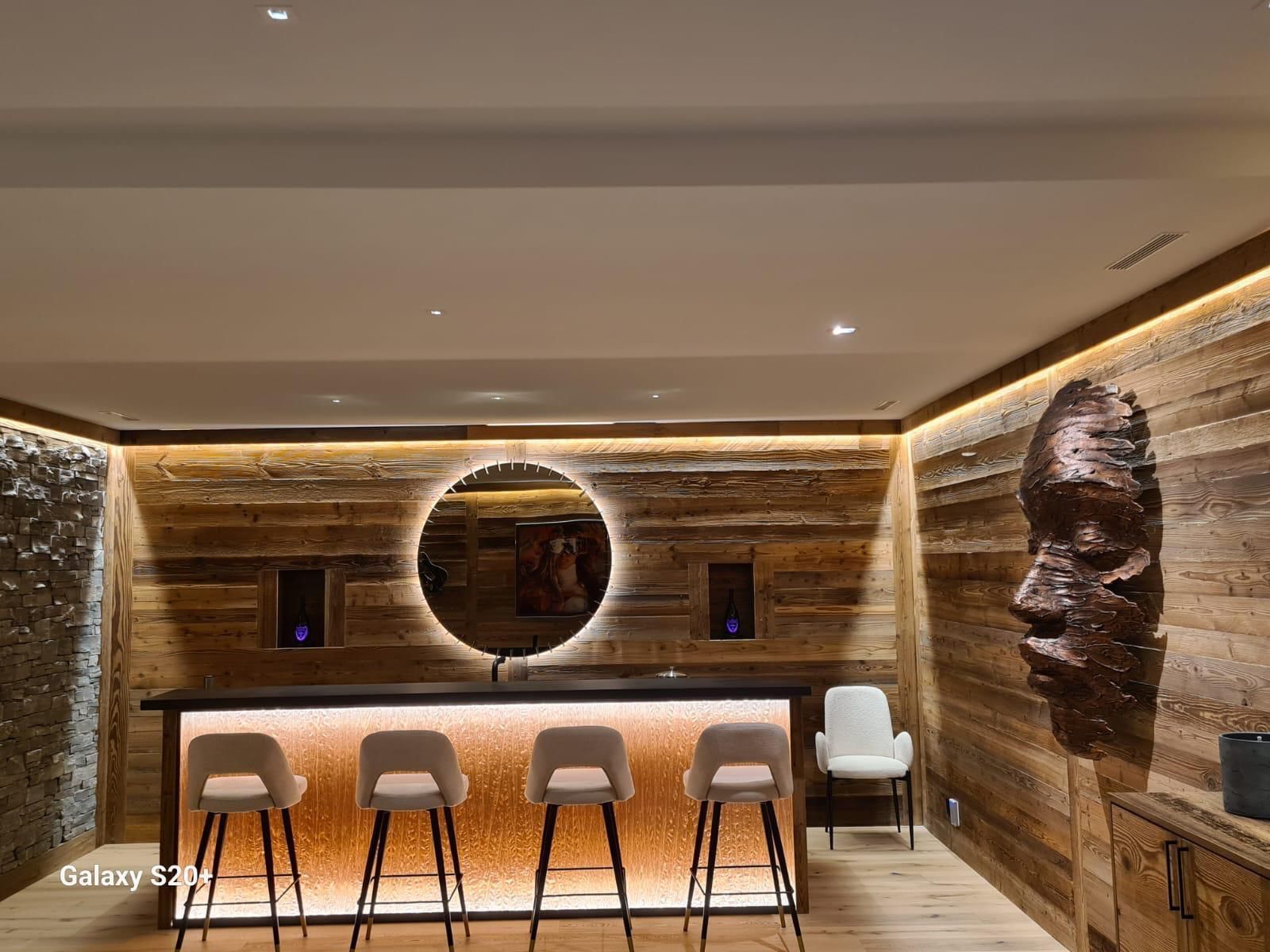 Un bar avec des tabourets et un miroir dans une pièce aux murs en bois.