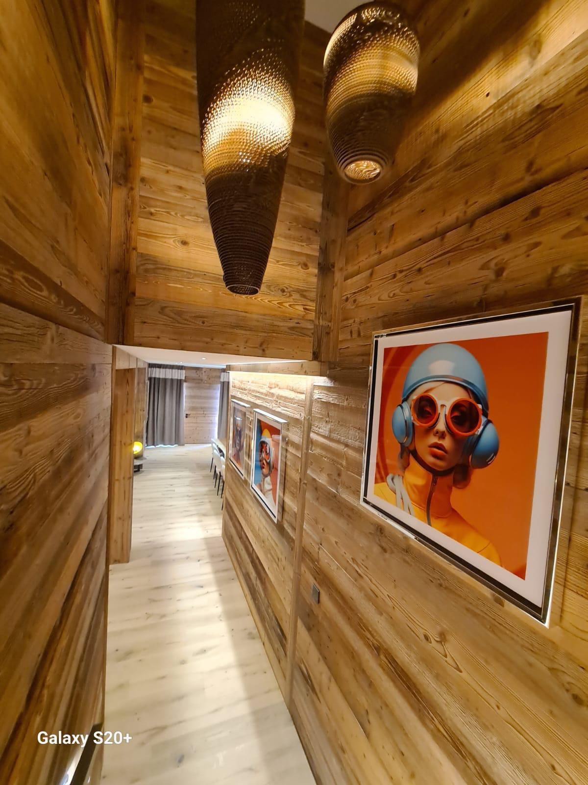 Un long couloir en bois avec une photo d'une femme portant des écouteurs et des lunettes de soleil sur le mur.