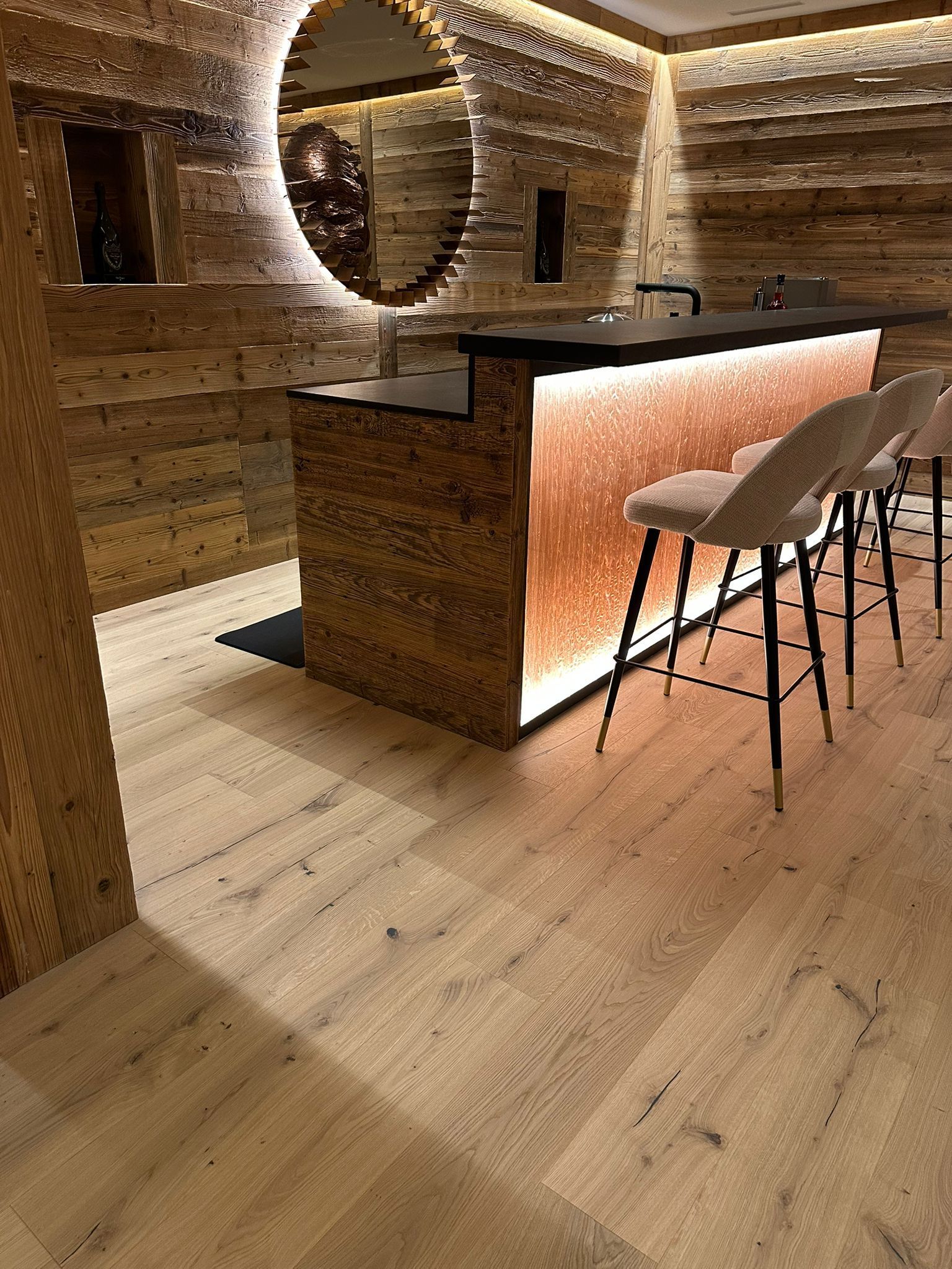 Un bar avec des tabourets et un miroir dans une pièce avec du parquet.