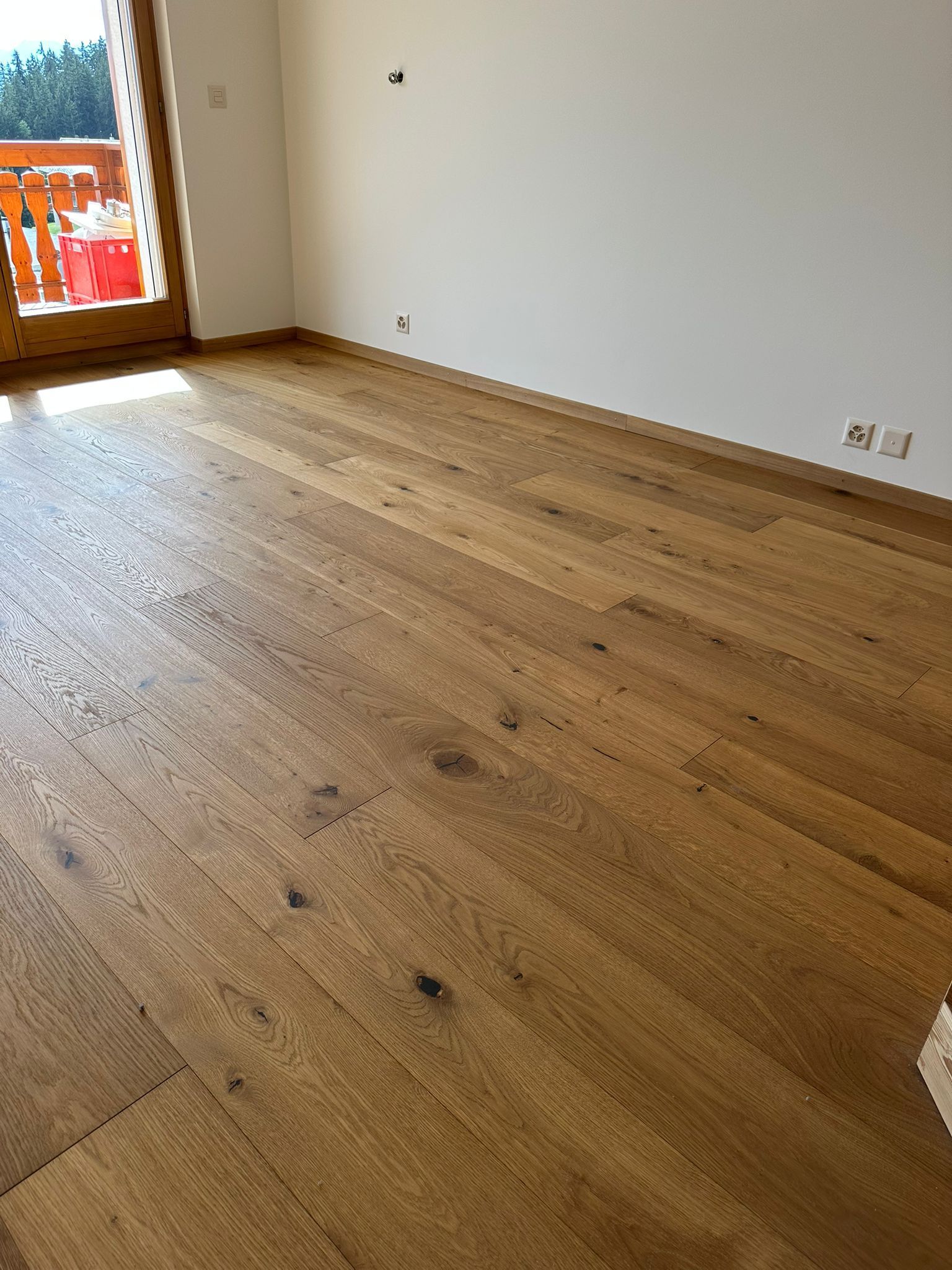 Une chambre avec un parquet et un balcon.