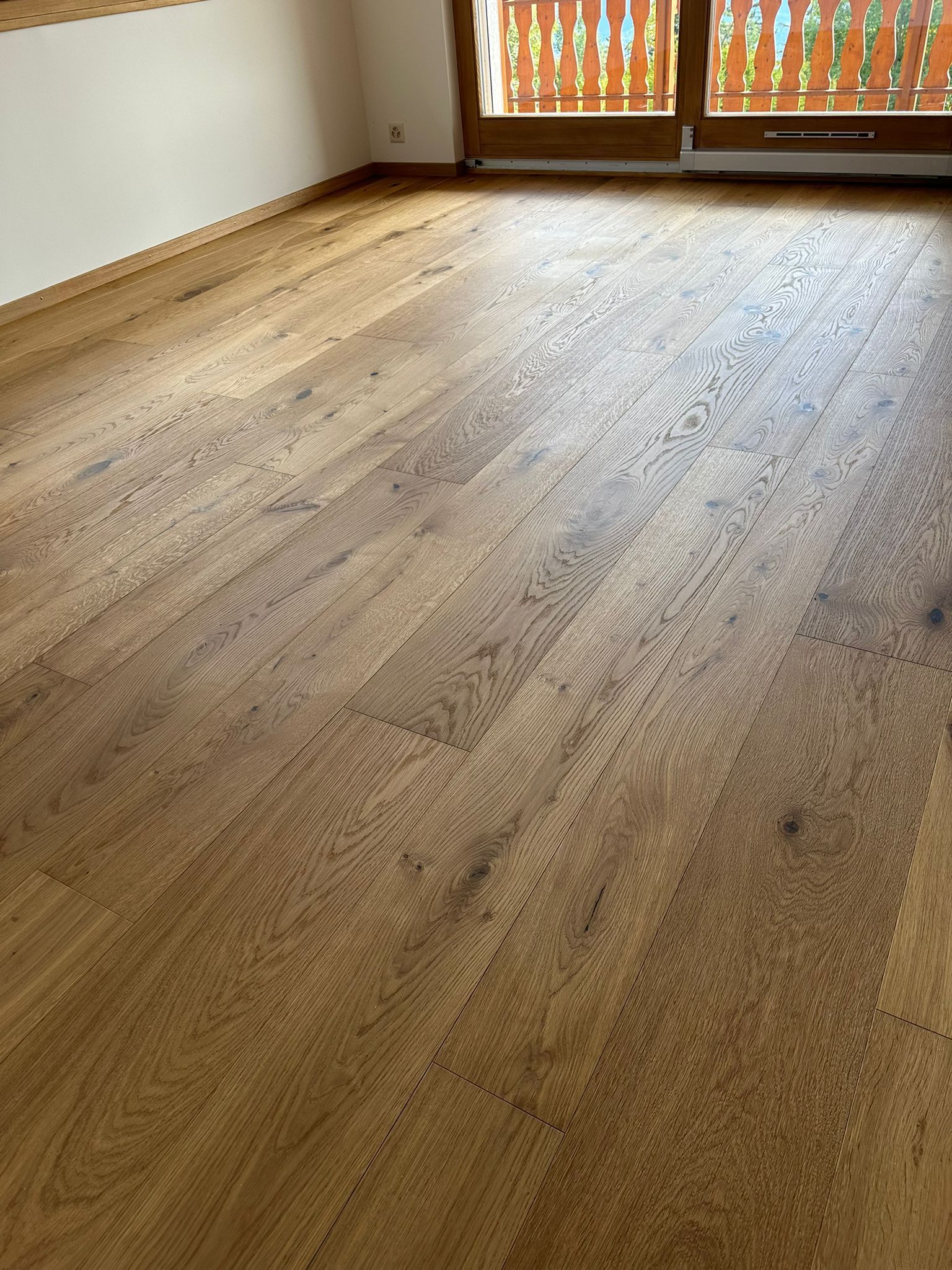 Une chambre avec un parquet et un balcon.