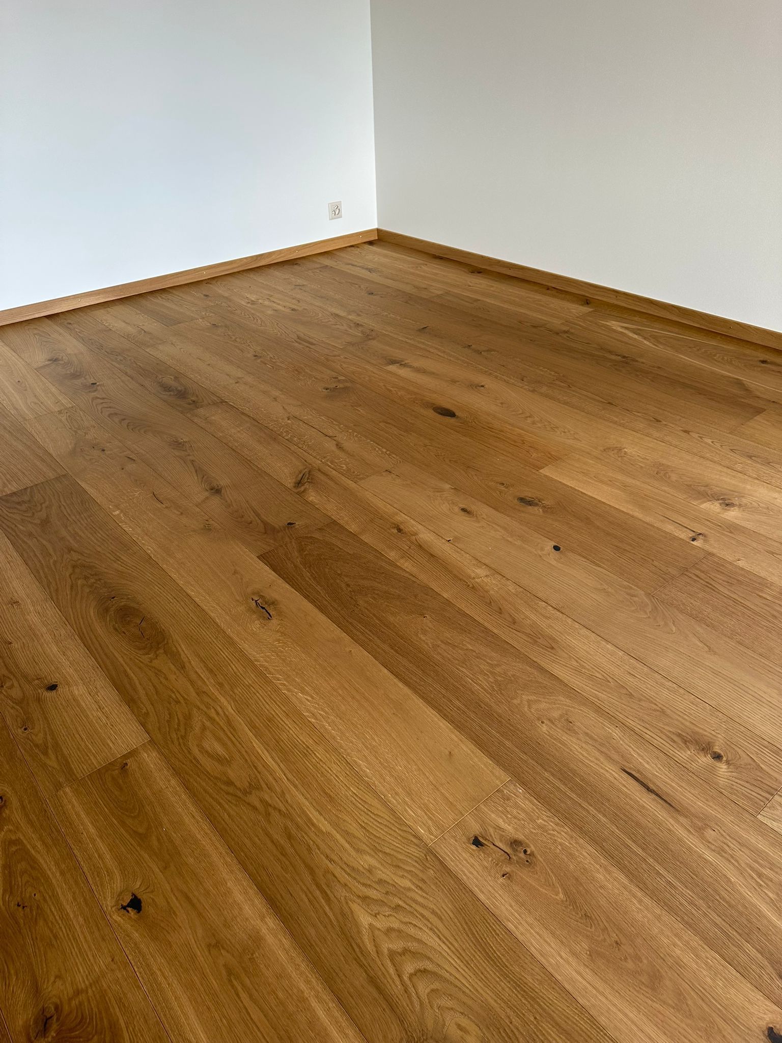 Une pièce avec un plancher en bois et des murs blancs.