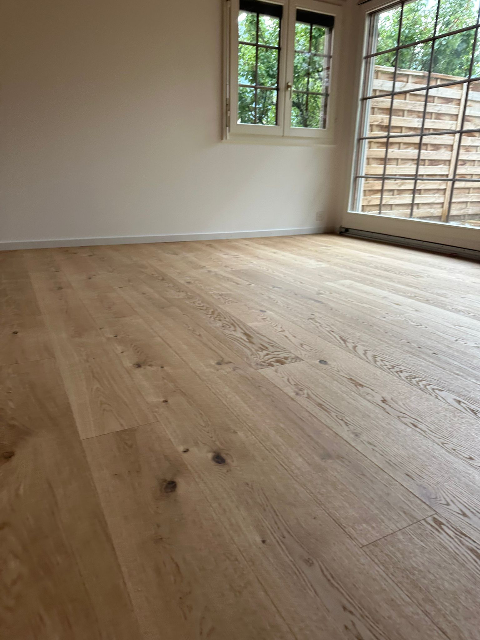 Une pièce vide avec un plancher en bois et une fenêtre.