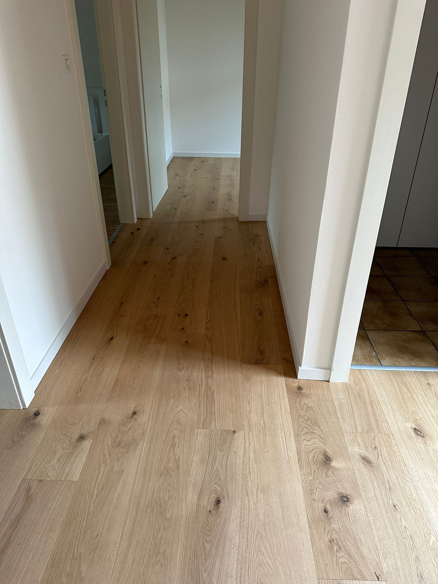 Un couloir avec du parquet et des murs blancs dans une maison.