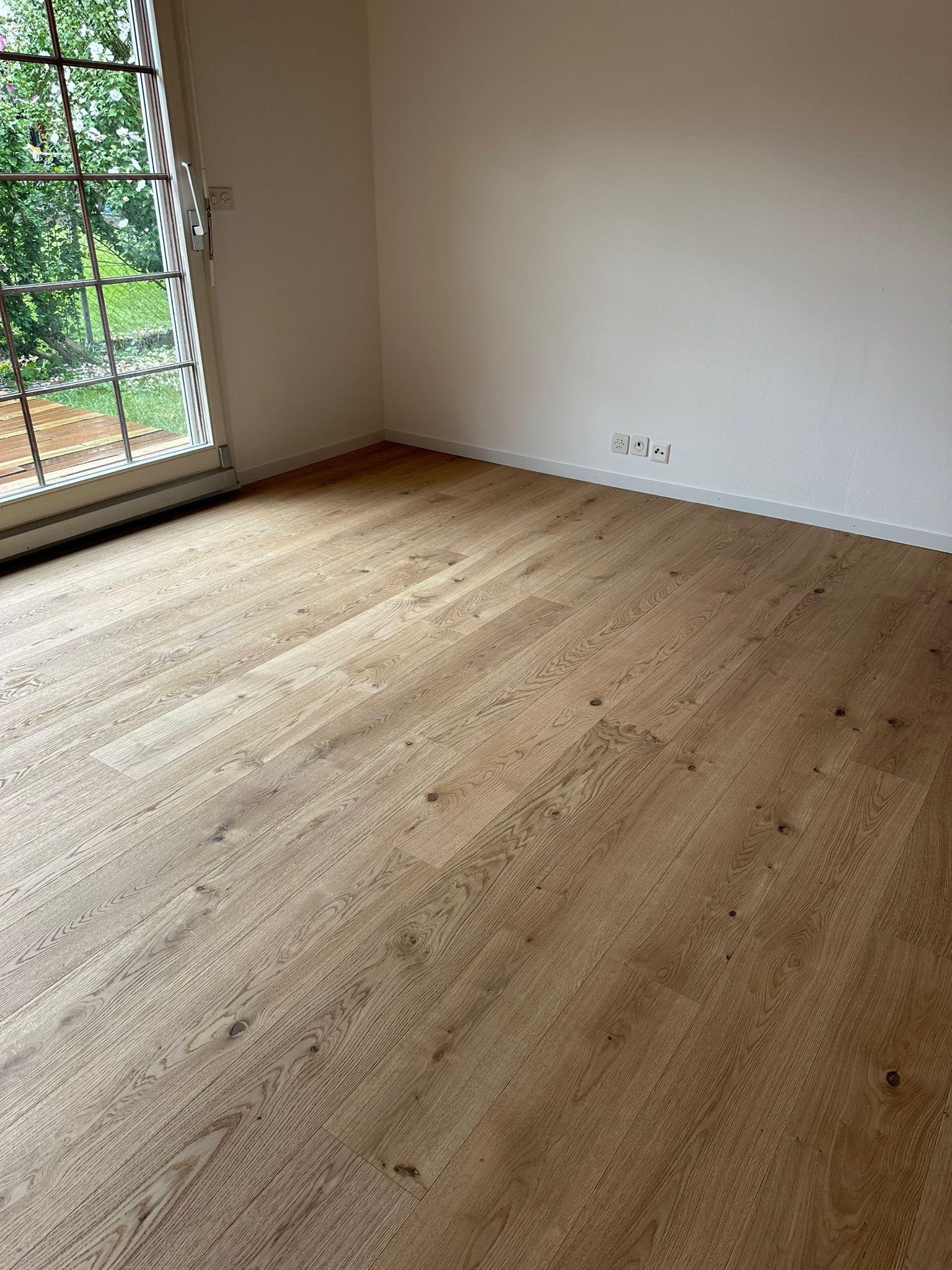Une pièce avec un plancher en bois et une fenêtre.