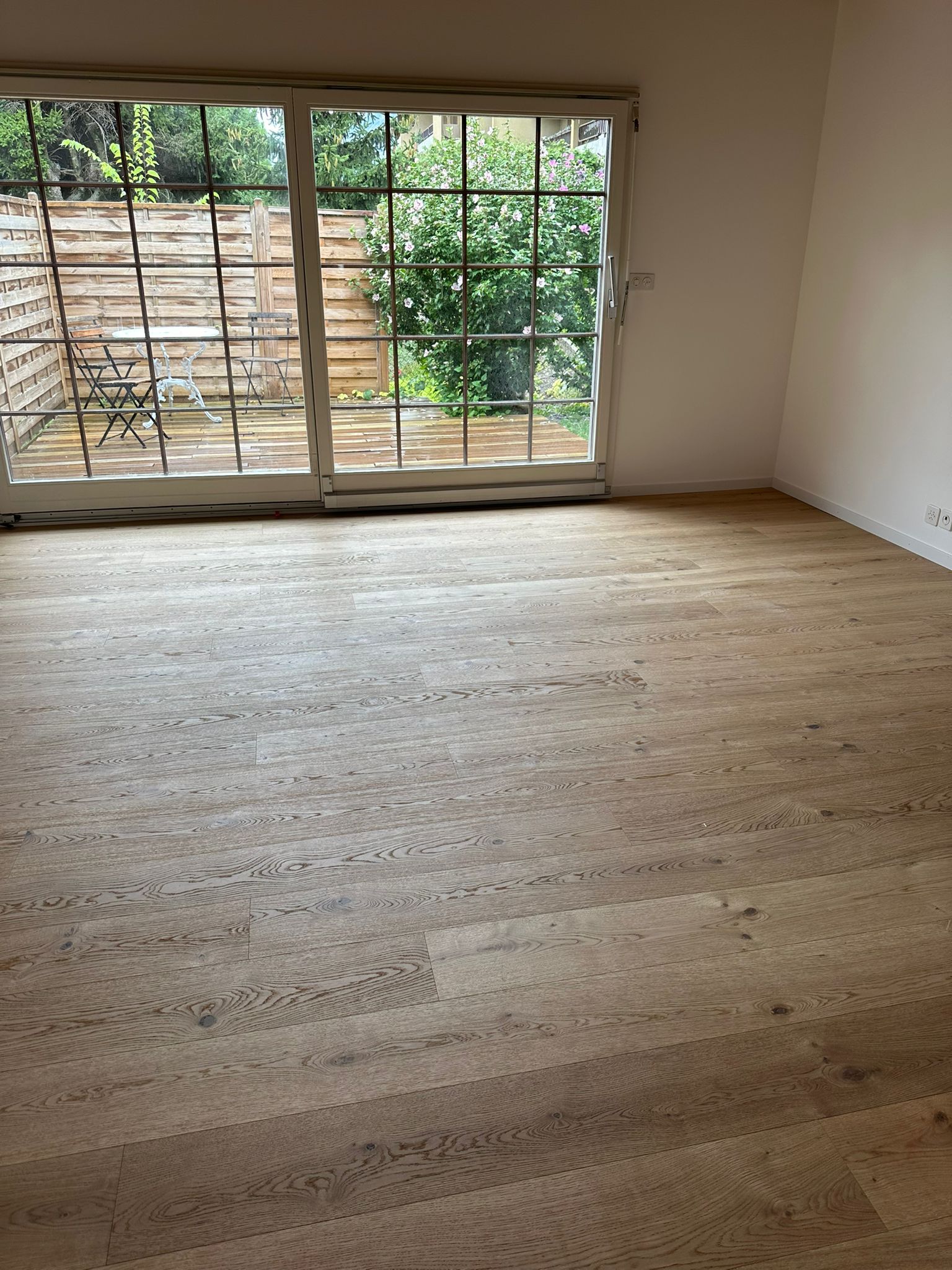 Une pièce vide avec un plancher en bois et une porte coulissante en verre.