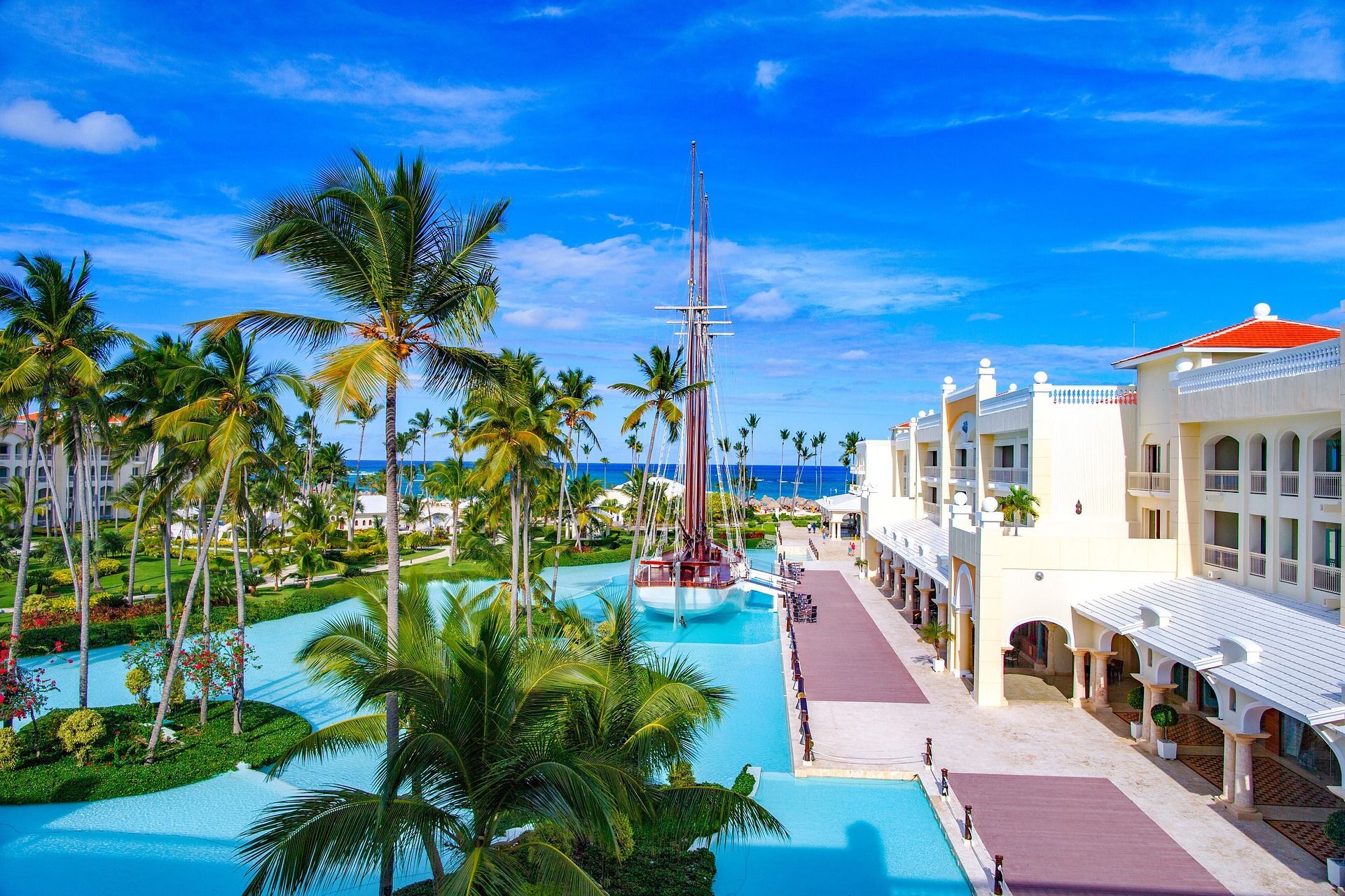 Tropical resort with blue pools, palm trees, and white buildings under a bright sky