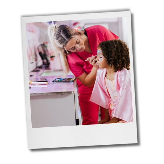 A woman is applying makeup to a little girl 's face.