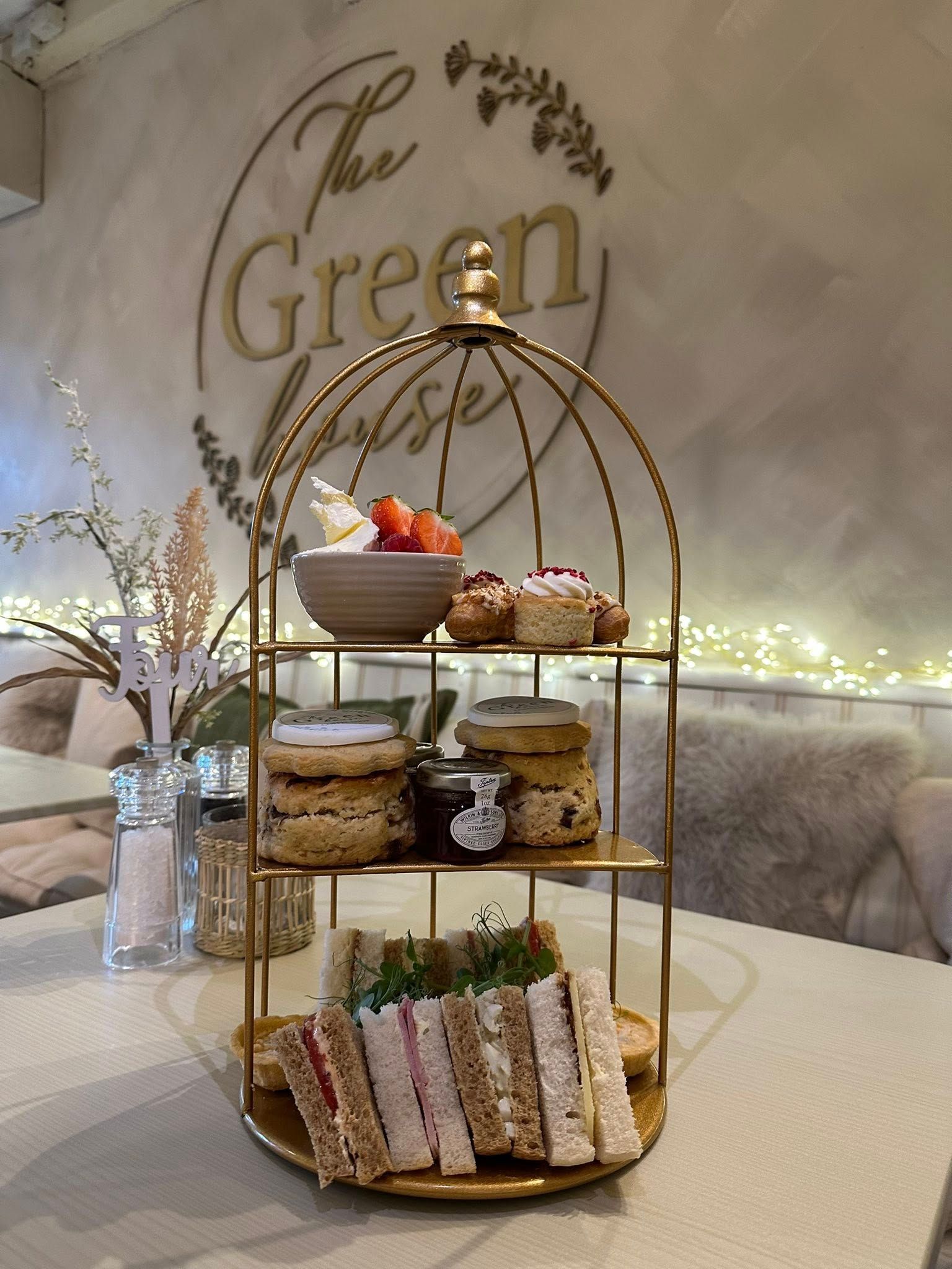 Tiered golden serving tray with food, table setting at The Green House cafe.