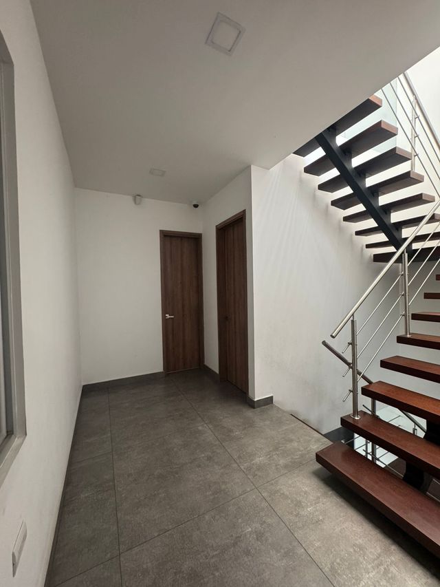 Pasillo con escaleras a la derecha y dos puertas cerradas. 