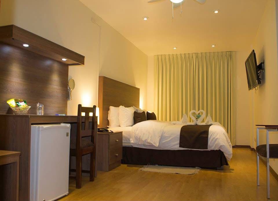 Habitación de hotel moderna con una cama grande, detalles en madera, escritorio e iluminación cálida.