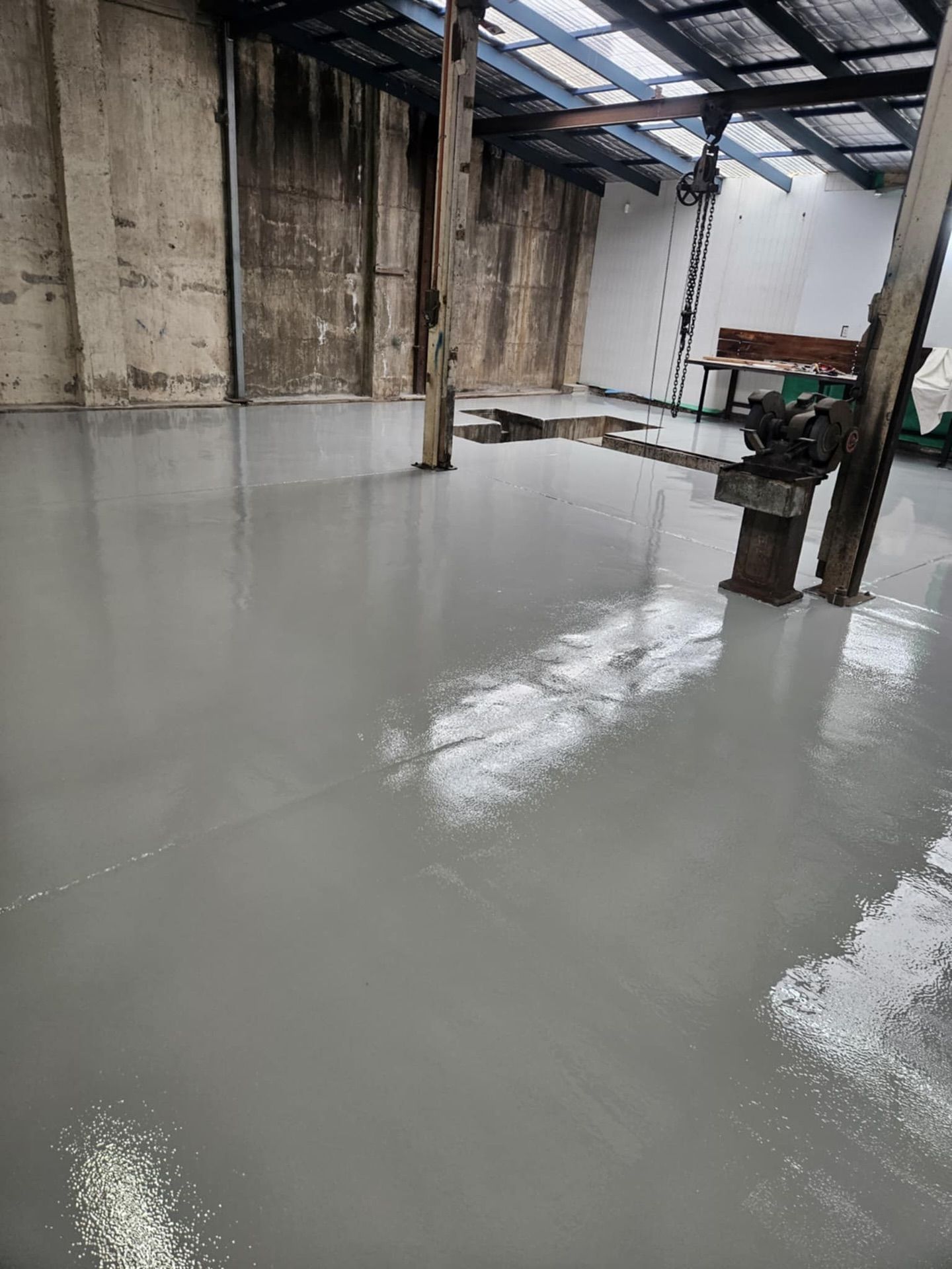 Interior of a building with a newly poured gray concrete floor; exposed beams and weathered walls — Riverina Epoxy Flooring In Glenfield Park, NSW