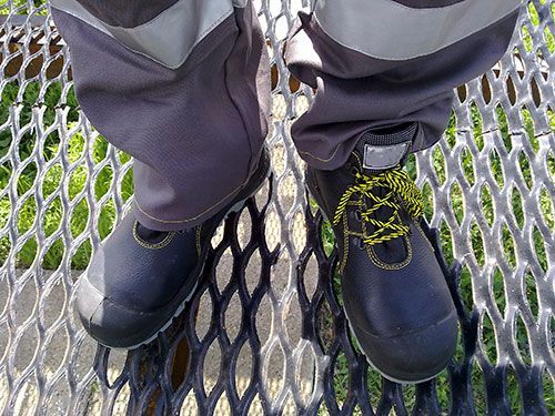 Una persona lleva un par de botas negras con cordones amarillos.