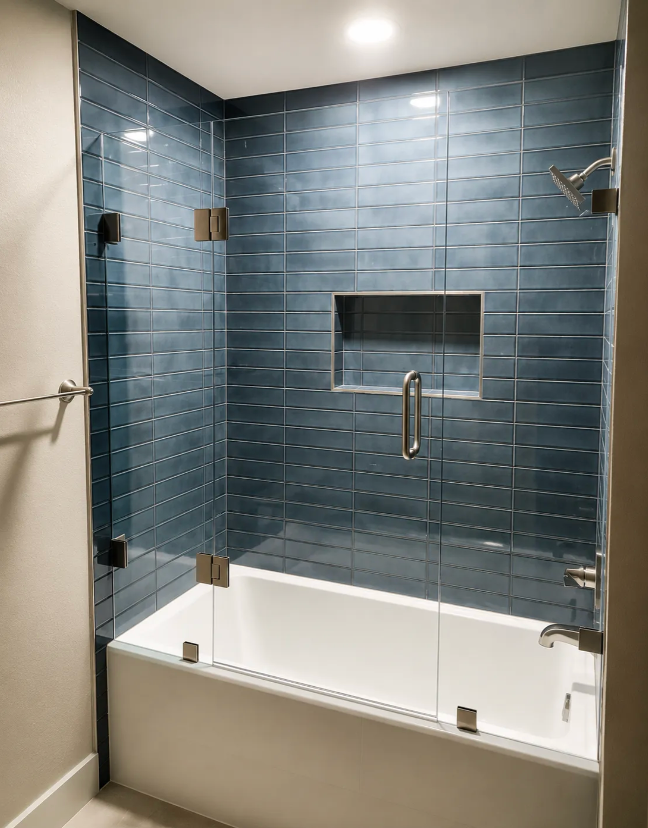 Modern bathroom with blue tiled glass shower and white tub built into the wall