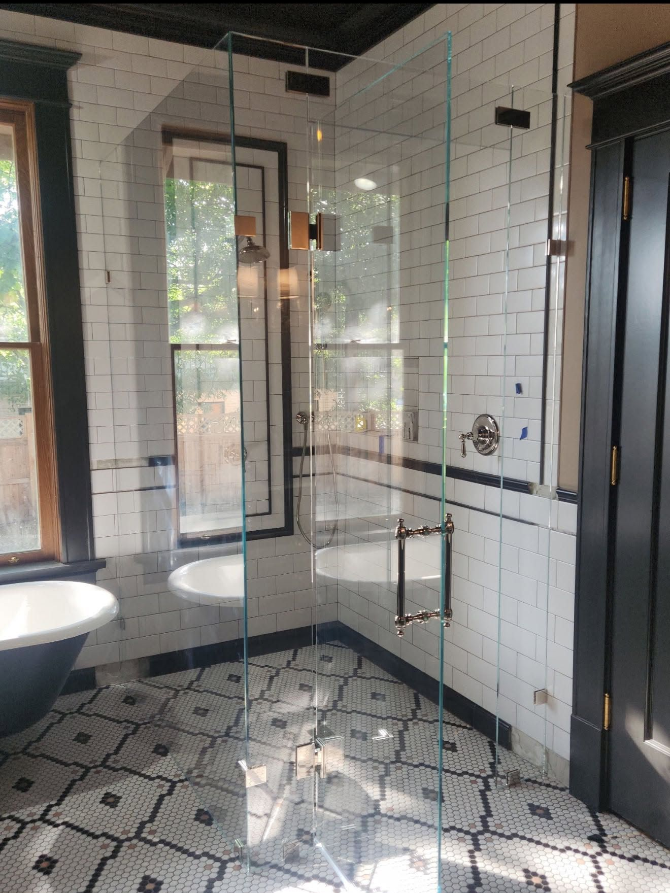 Modern bathroom with glass shower, white subway tile, black trim, and patterned floor tiles