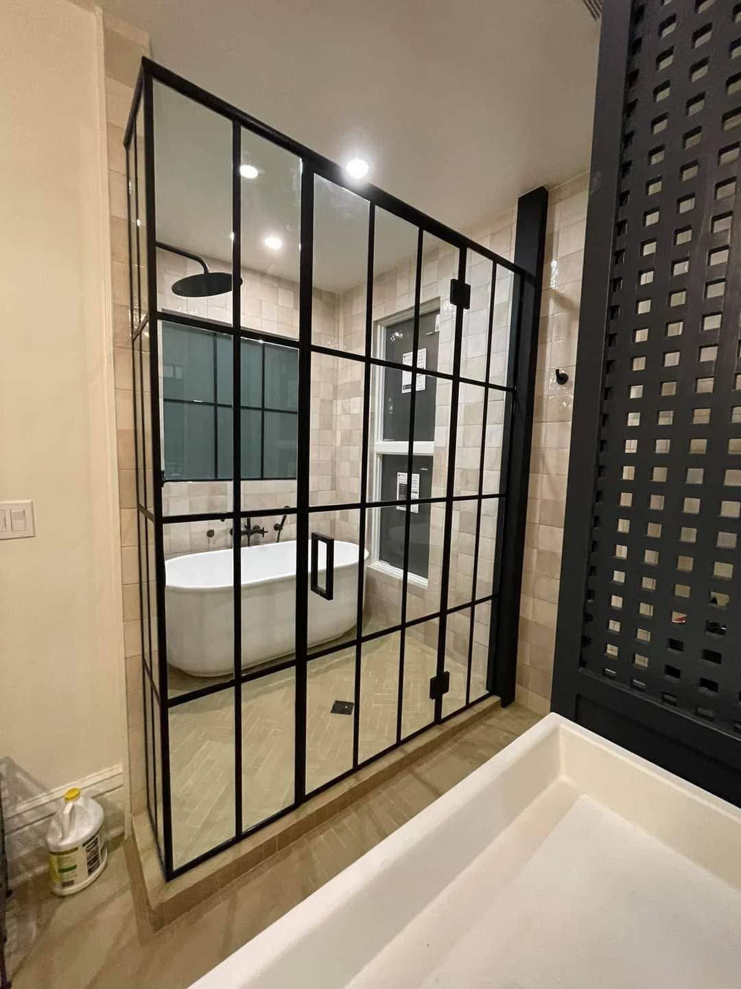 Modern bathroom with black-framed glass shower door and white freestanding tub